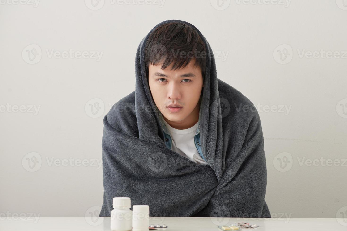 a man wrapped in a warm blanket basks on a light background photo