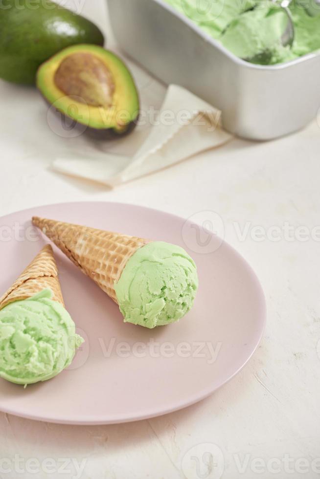 Green avocado ice cream scoops in wafle cones on white background. Copy