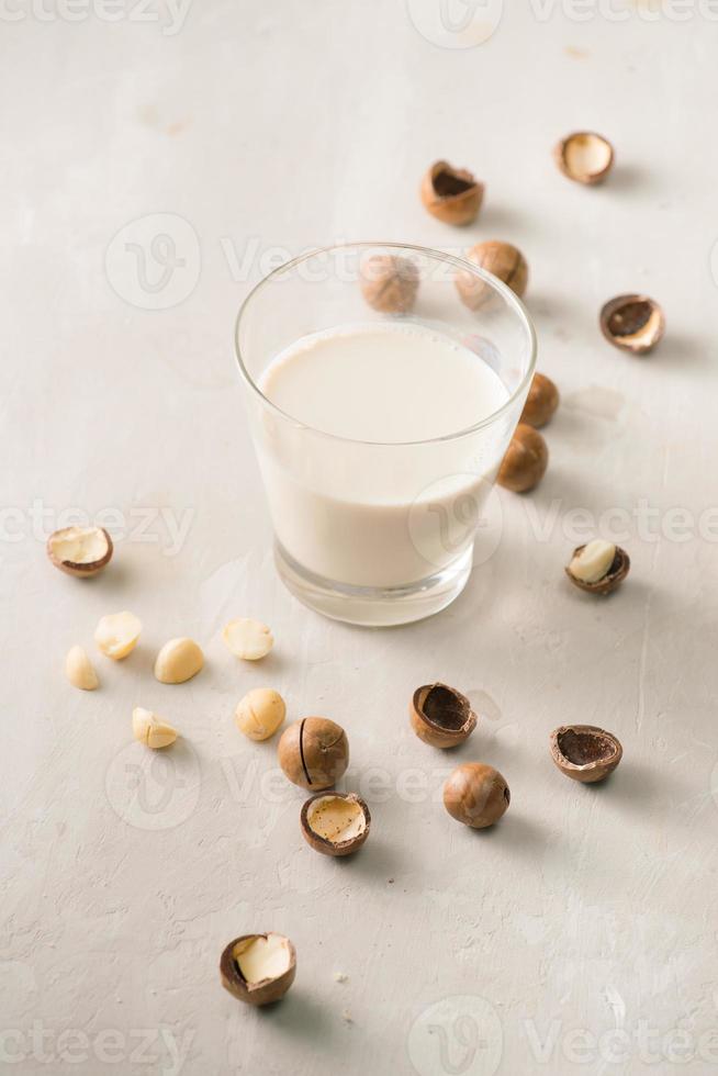 Superfood. Organic macadamia nuts and glass of macadamia milk on stone background. photo