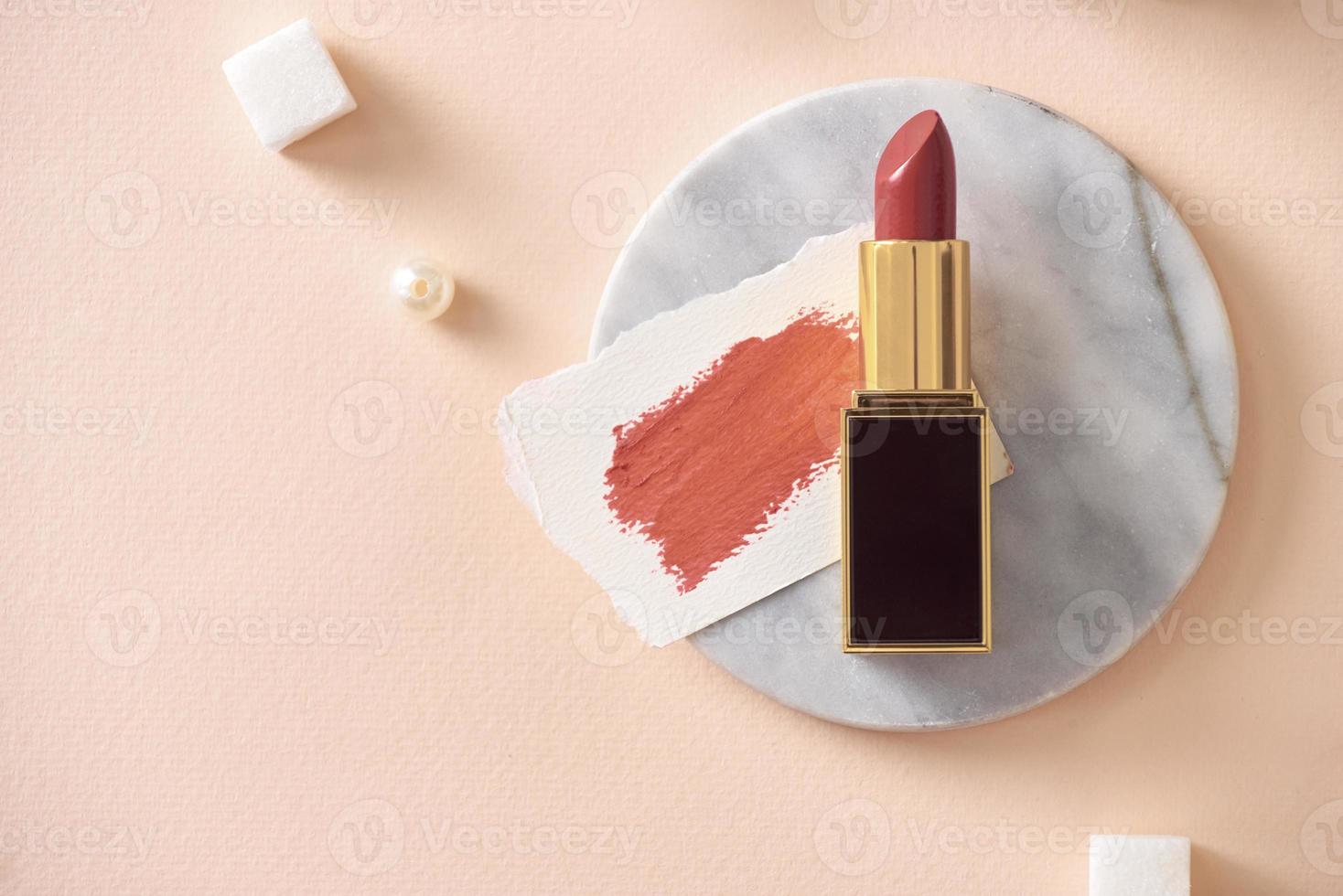 lápiz labial rojo y sus frotis aislados en piel naranja foto