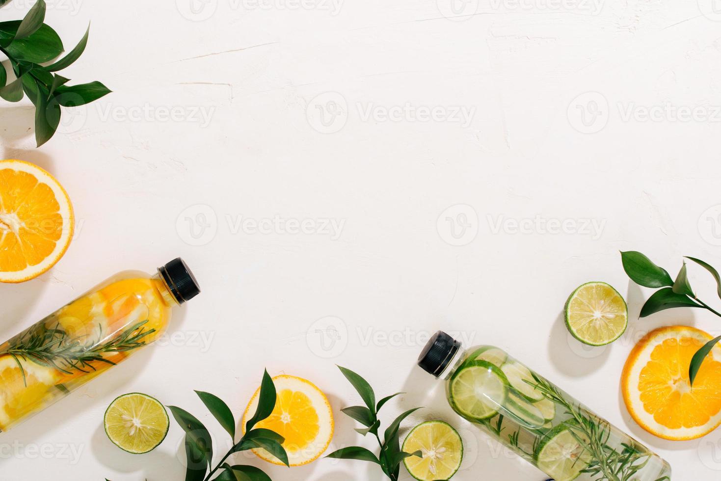 Leaves and bottle tropical water on white background. Detox fruit infused water, citrus fruits and rosemary leaves. Top view, flat lay, copy space photo