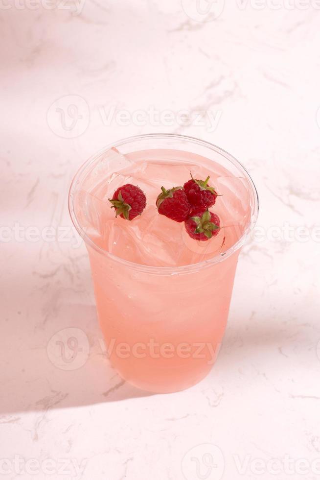 Summer juice with fresh raspberries in a glass on a light background photo