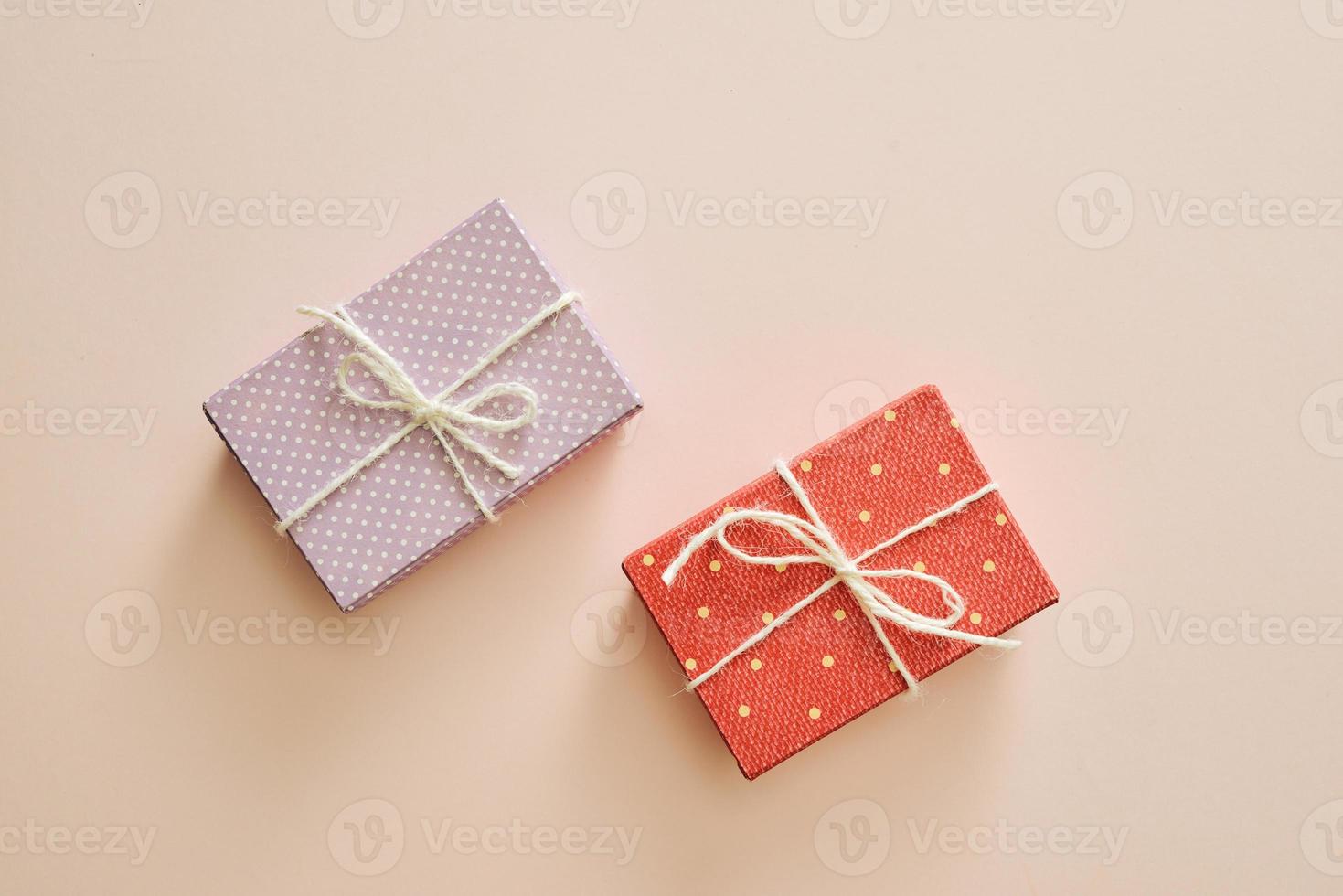 Two gift boxes wrapped in color purple and red polka dots paper on pink background. photo