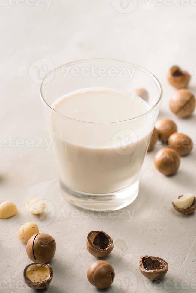 Superfood. Organic macadamia nuts and glass of macadamia milk on stone background. photo