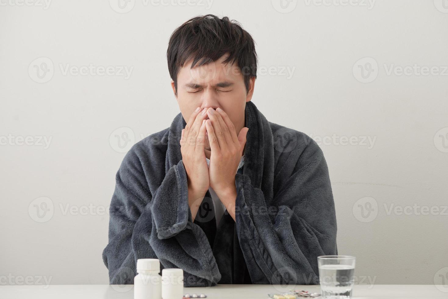 joven enfermo y enfermo en el sofá sosteniendo tejido limpiando la nariz mocosa con temperatura sintiéndose mal infectado por el virus de la gripe invernal en el concepto de atención médica de la gripe y la influenza. foto