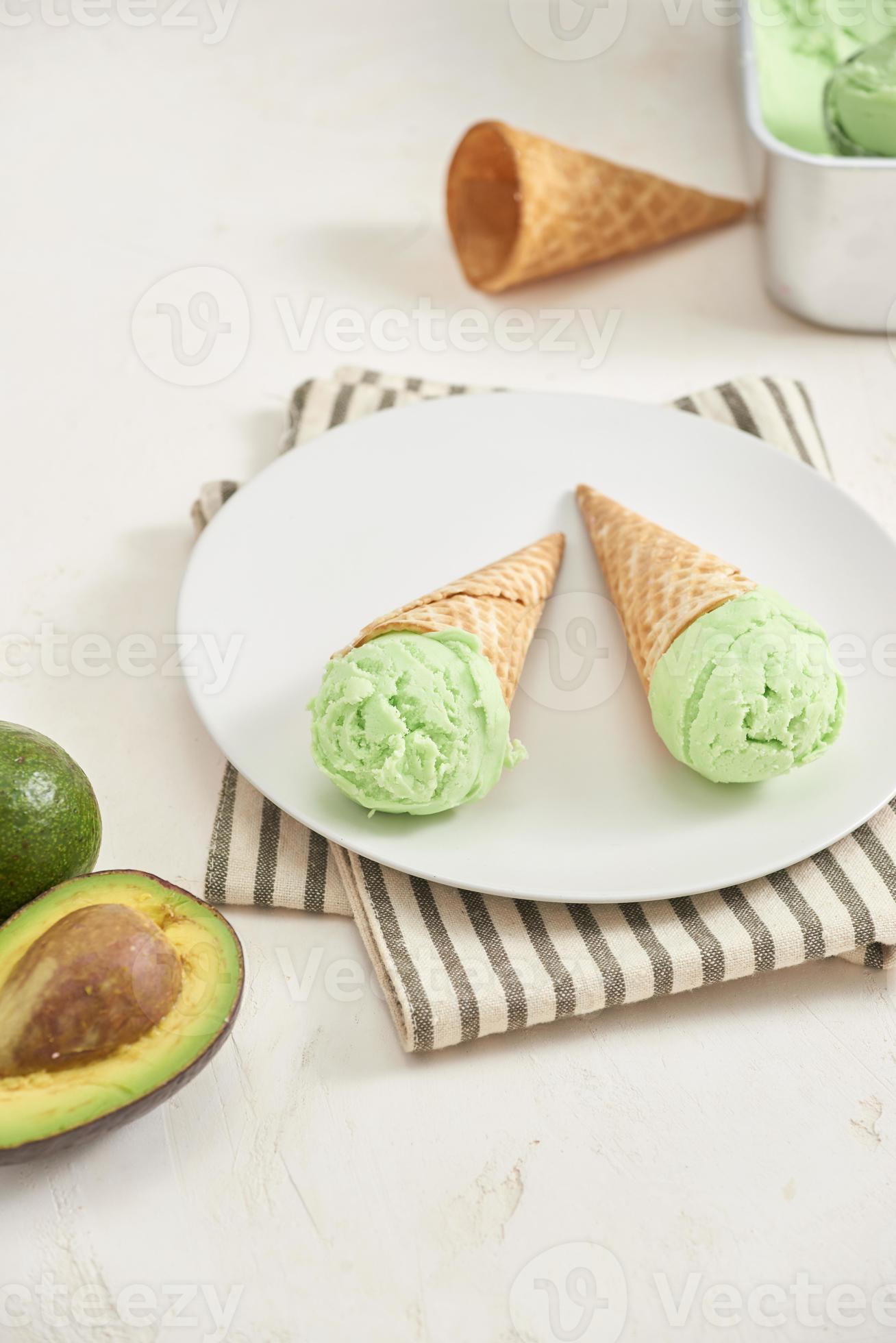Green avocado ice cream scoops in wafle cones on white background. Copy