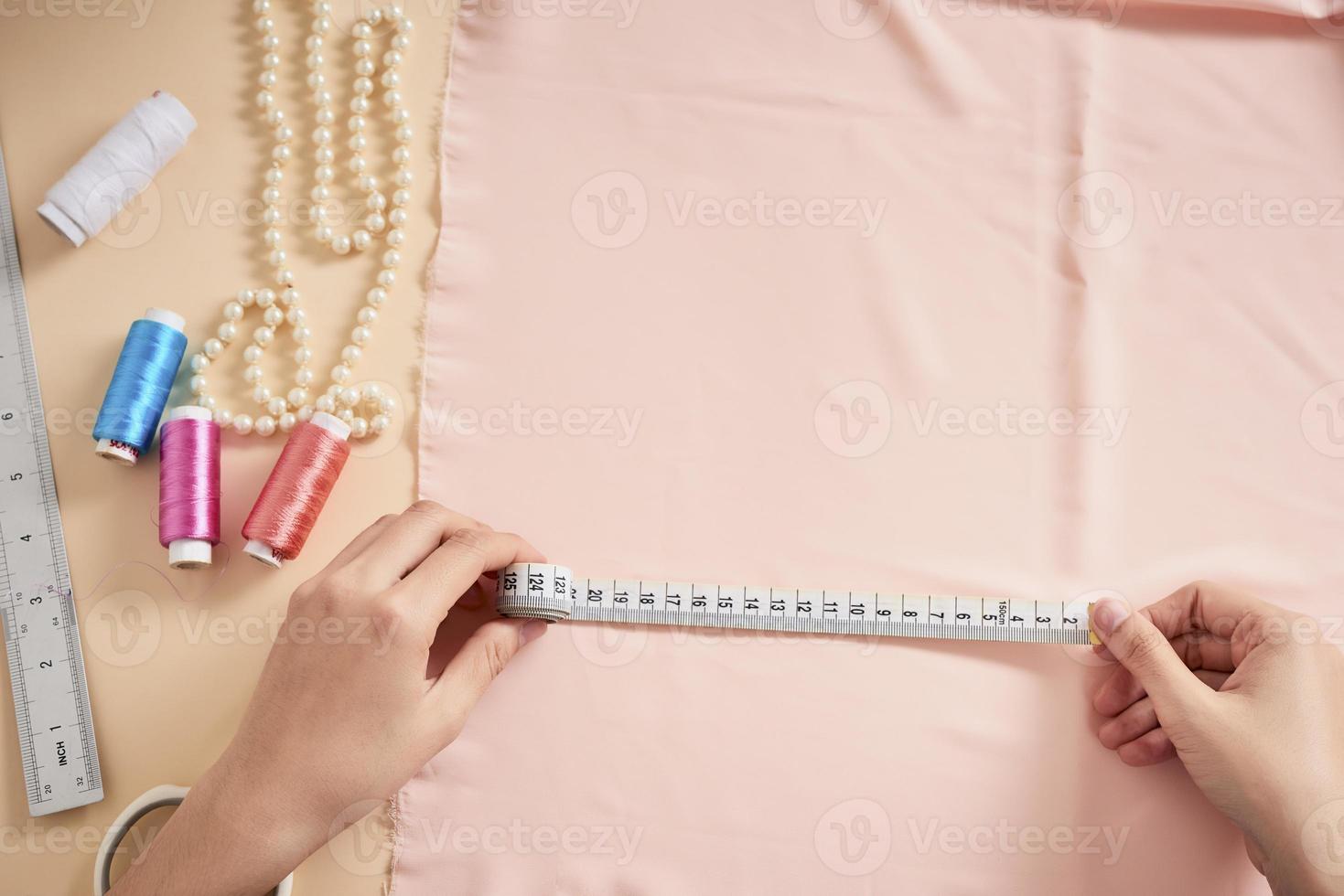 Fashion designer, Woman tailor posing at her workplace with cut fabric, free space on table. Garment industry, tailoring concept photo