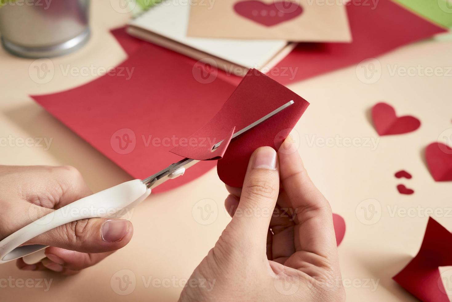 mujer corta corazones de fieltro rojo, artesanía casera para el día de san valentín, creatividad hecha a mano, vista superior foto