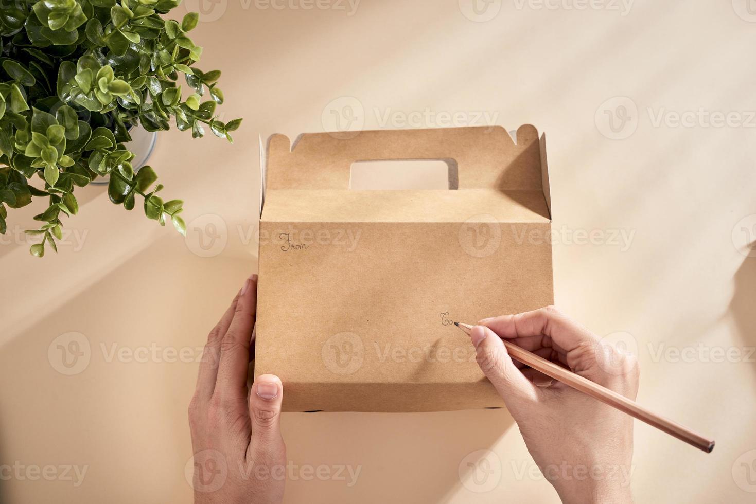 Cropped image of woman writing best wishes on box with present photo