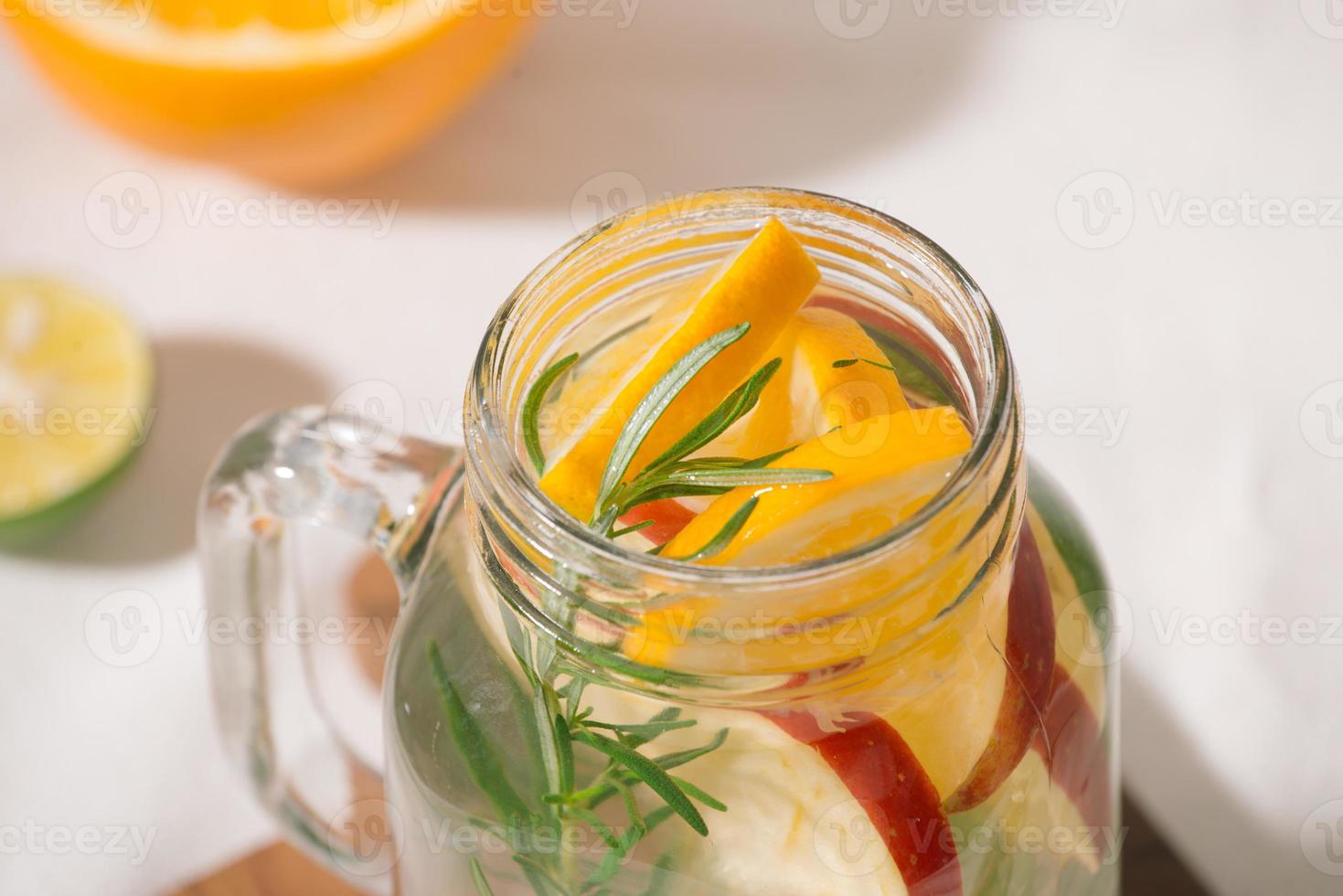 Infused water with lime, orange, apple and rosemary. Cold refreshing detox summer drink .Selective focus photo