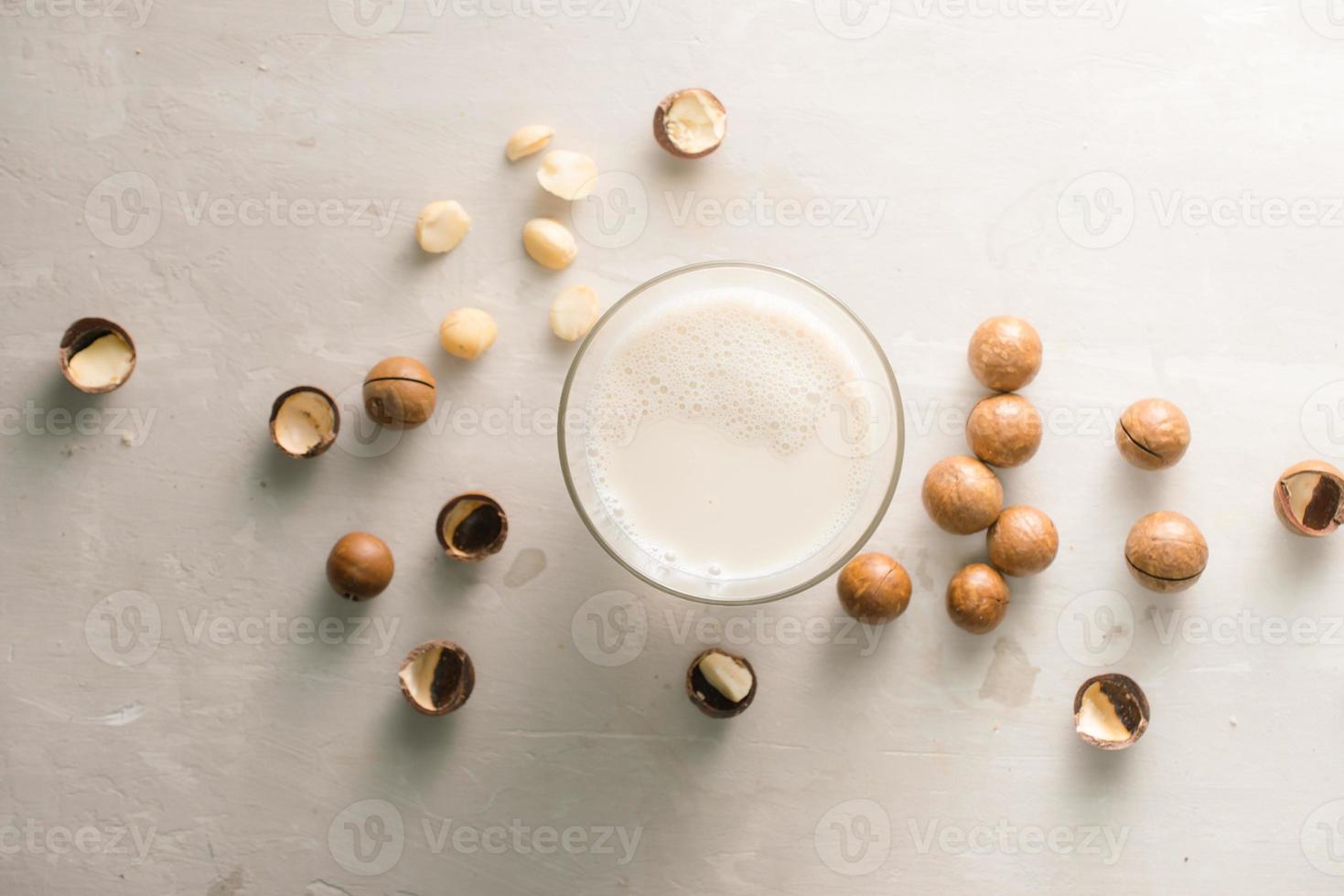 Superfood. Organic macadamia nuts and glass of macadamia milk on stone background. photo