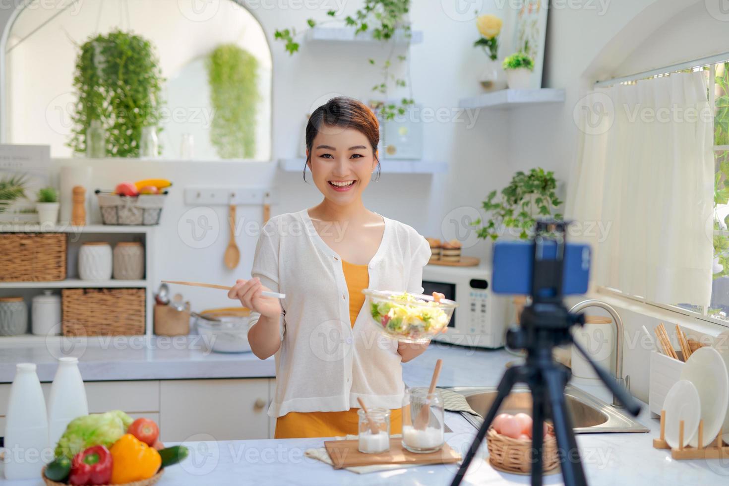blogger de comida grabando video con cámara de teléfono en la cocina de casa foto