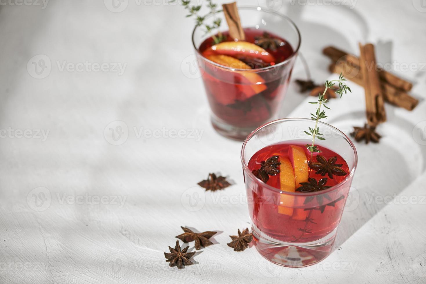 cóctel de naranja con ron, licor, rodajas de pera y tomillo sobre mesa blanca, enfoque selectivo foto