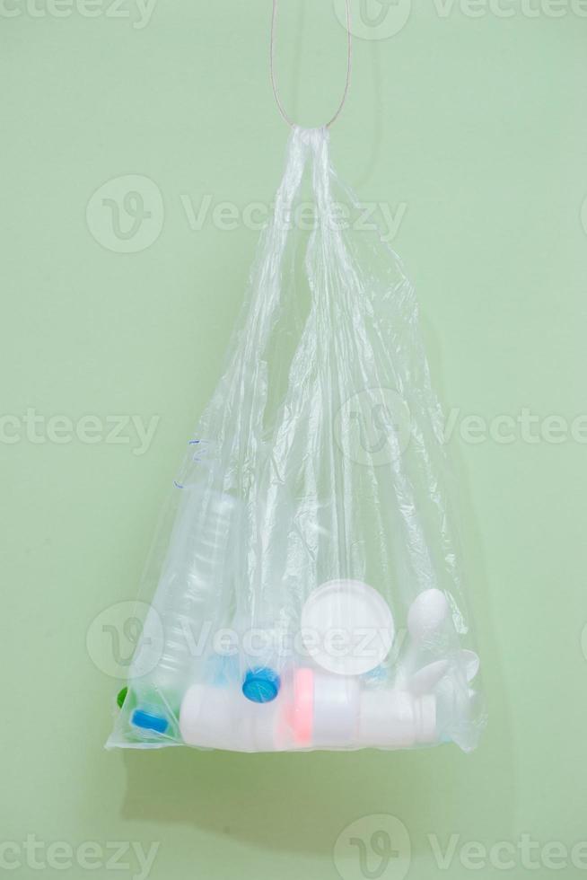 Plastic bag filled with household waste isolated on white background. photo