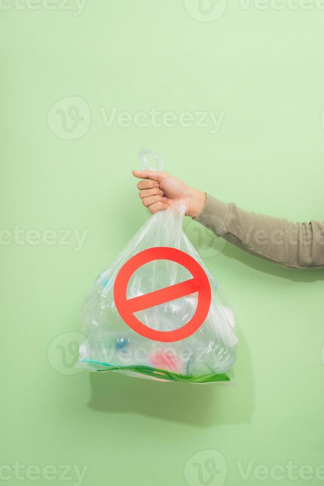 Male hand holding a waste bag isolated on green background. photo