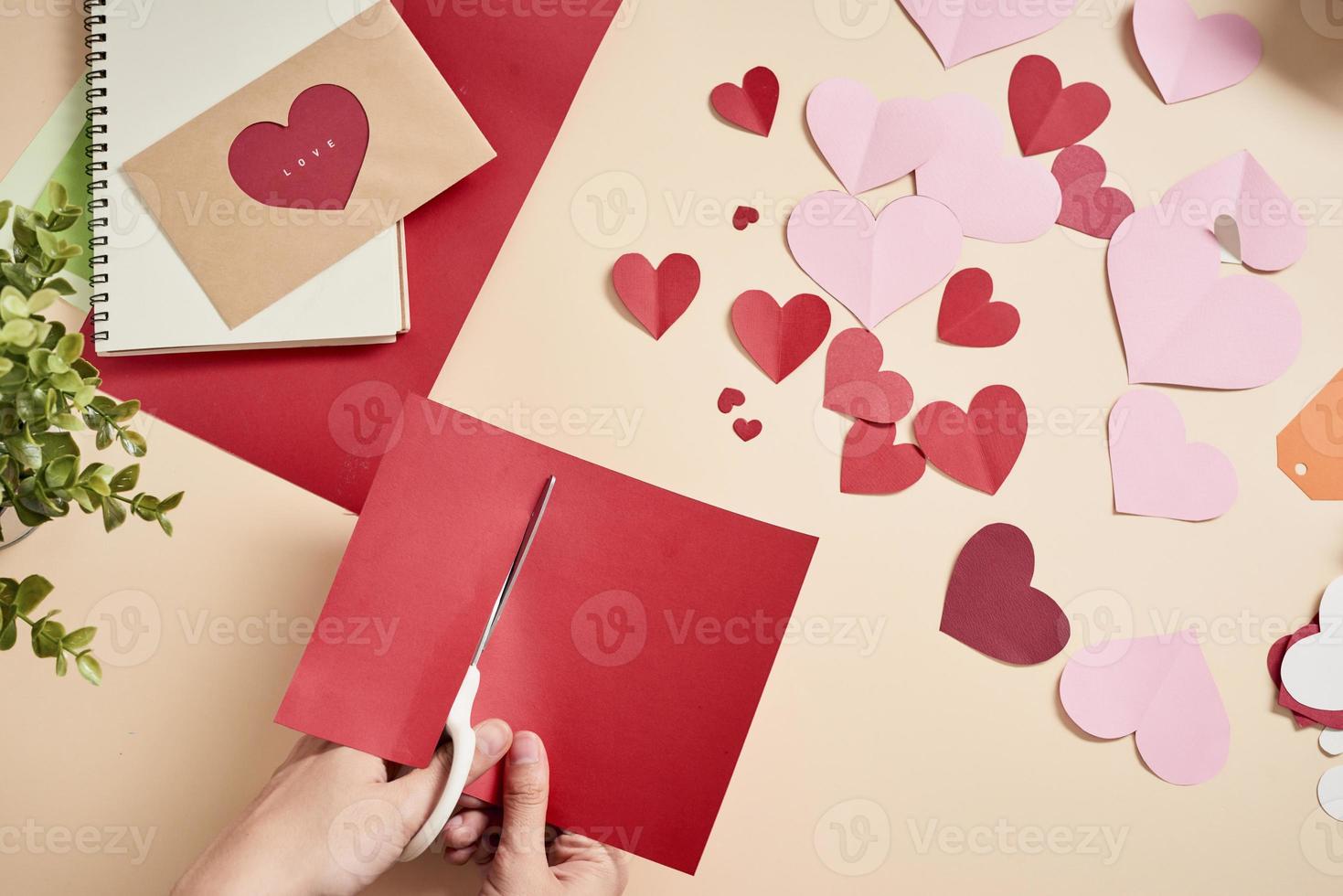 woman cuts out red felt hearts, homemade crafts for Valentine's day, hand made creativity, top view photo