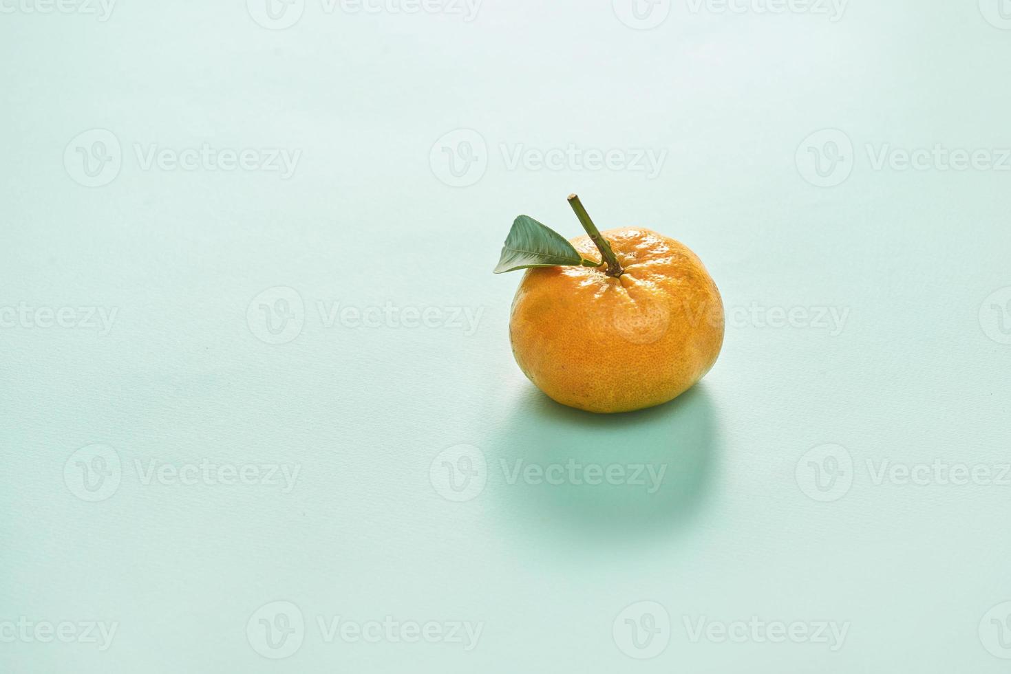 Tangerine or clementine with green leaf isolated on blue background - Image photo