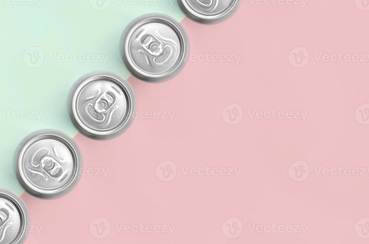 Many metallic beer cans on texture background of fashion pastel turquoise and pink colors photo