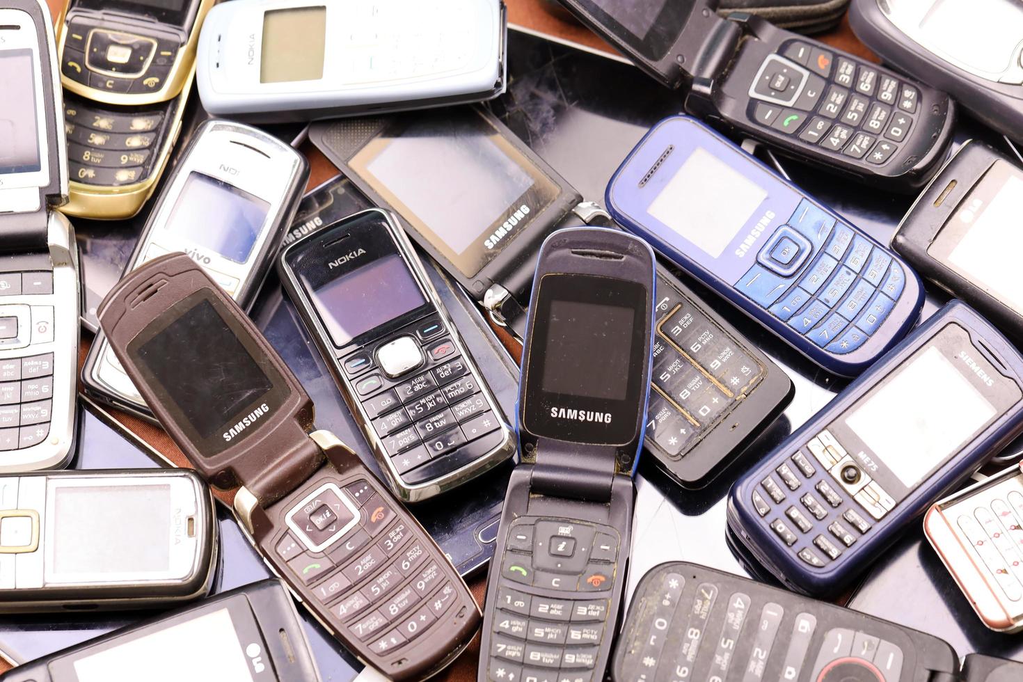 KHARKIV, UKRAINE - DECEMBER 16, 2021 Some old used outdated mobile phones from 90s-2000s period. Recycling electronics in the market photo