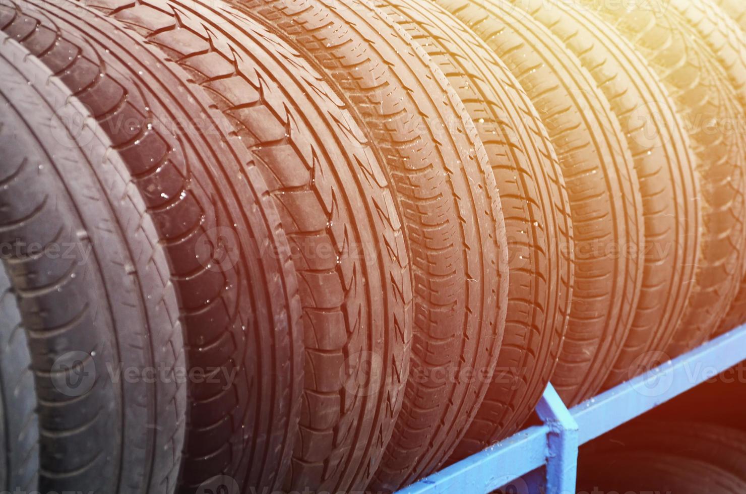 Rack with variety of car tires in automobile store. Many black tires. Tire stack background. Selective focus photo