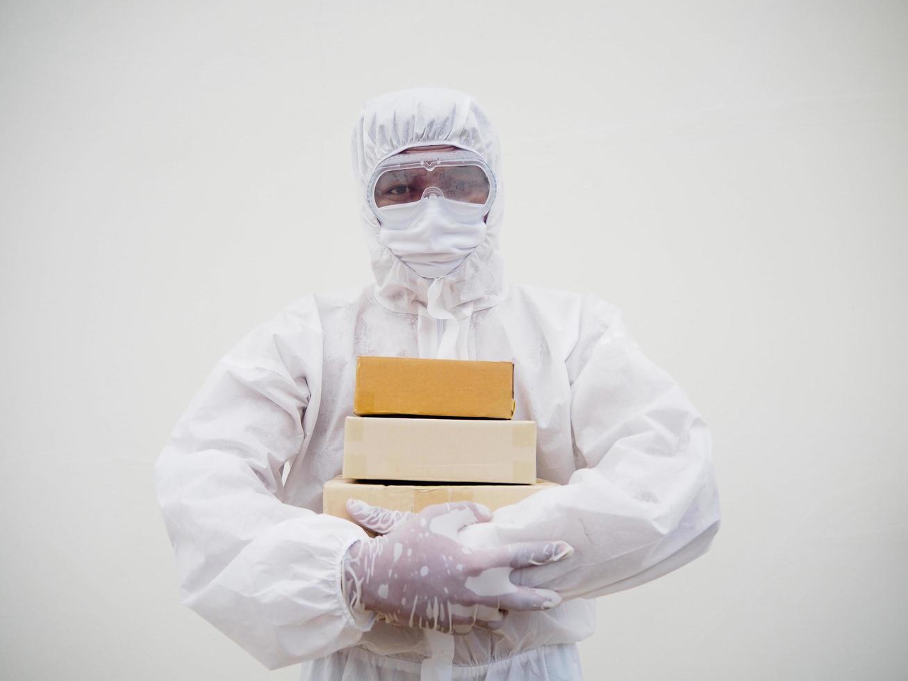 Young man in PPE suite uniform while holding cardboard boxes in medical rubber gloves and mask. coronavirus or COVID-19 concept isolated white background photo