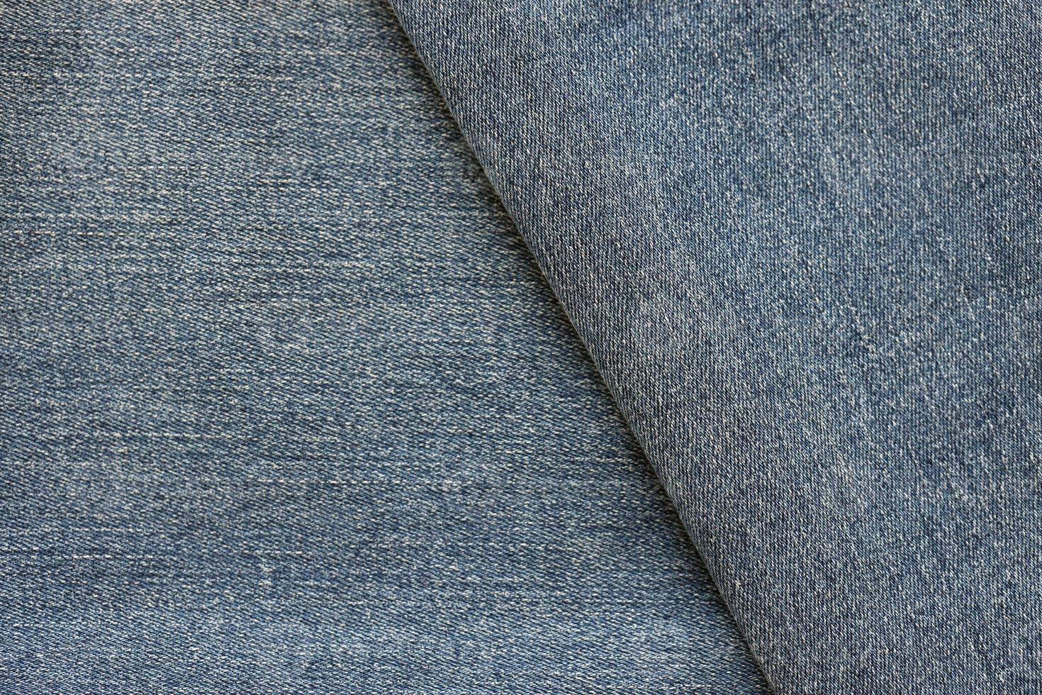 Detailed abstract texture of dark blue denim cloth. Background image of old used denim trousers fabric photo