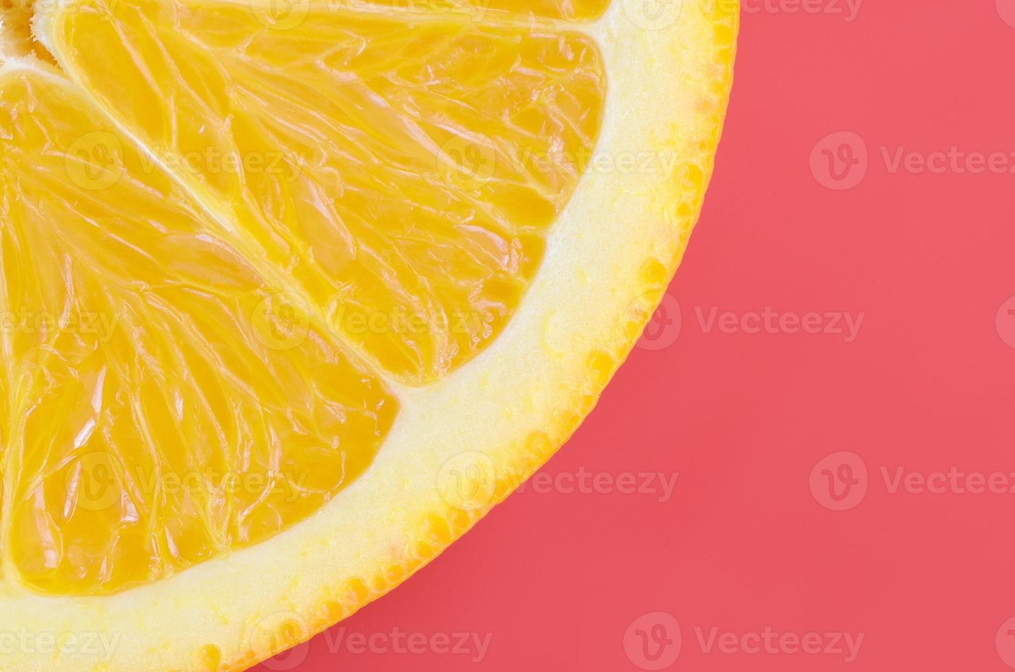 Top view of a one orange fruit slice on bright background in red color. A saturated citrus texture image photo