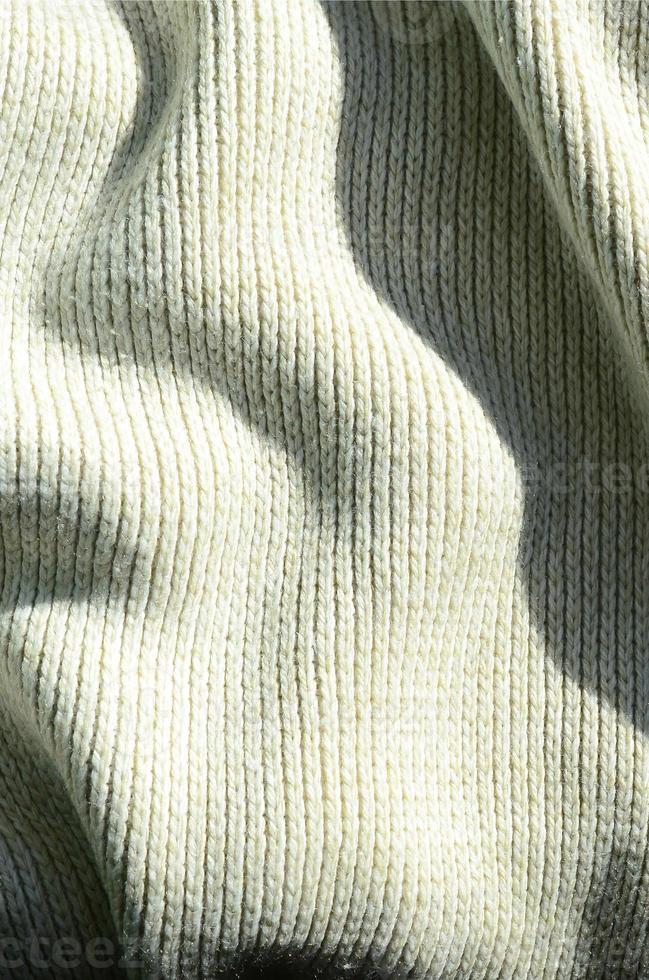 Fabric texture of a soft yellow knitted sweater. Macro image of the structure of bindings in yarns photo