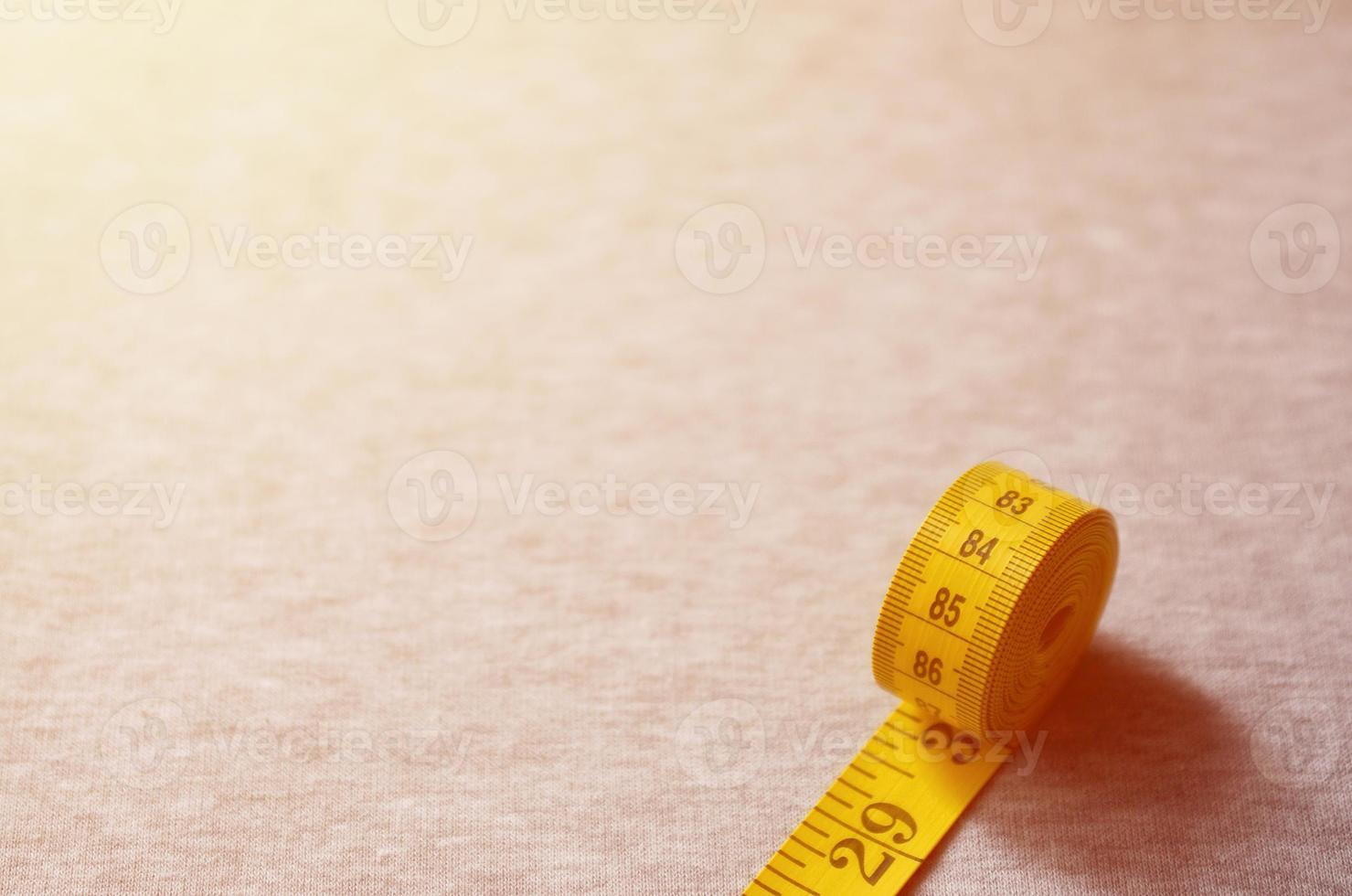 Yellow measuring tape lies on a gray knitted fabric photo