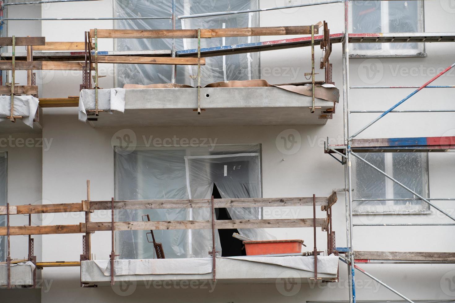Detail shot of the facade of a new house under construction. The balconies are provisionally secured with wooden slats. The windows are sealed with foil. photo