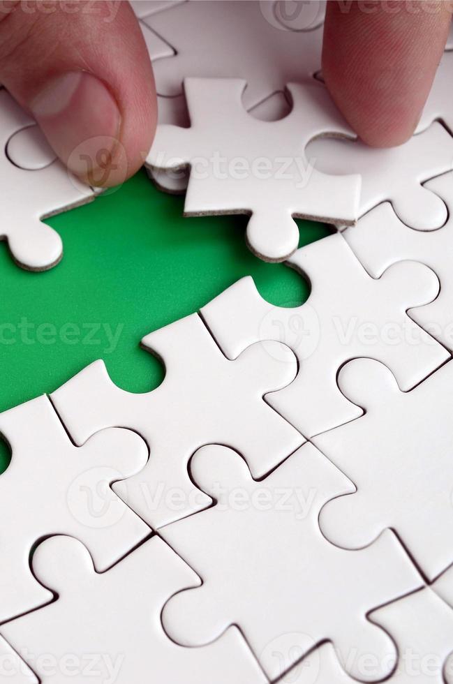 The human hand paves the way to the surface of the jigsaw puzzle, forming a green space. The concept of overcoming the difficulties on the way to success photo