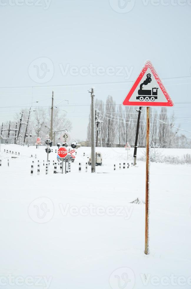 Railway crossing without a barrier with a lot of warning signs in the snowy winter season photo