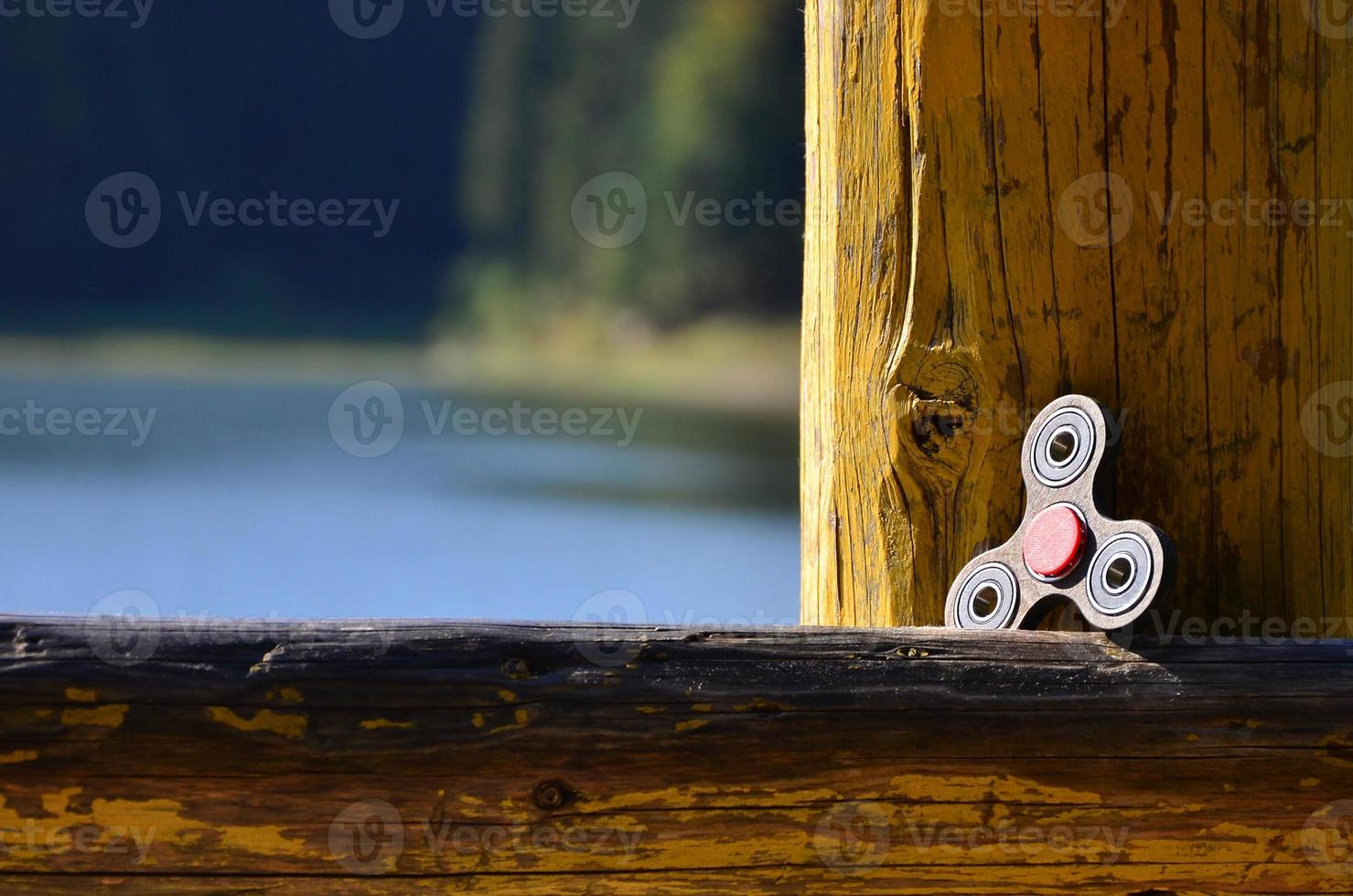 A wooden spinner lies on a wooden bar against a background of river water photo