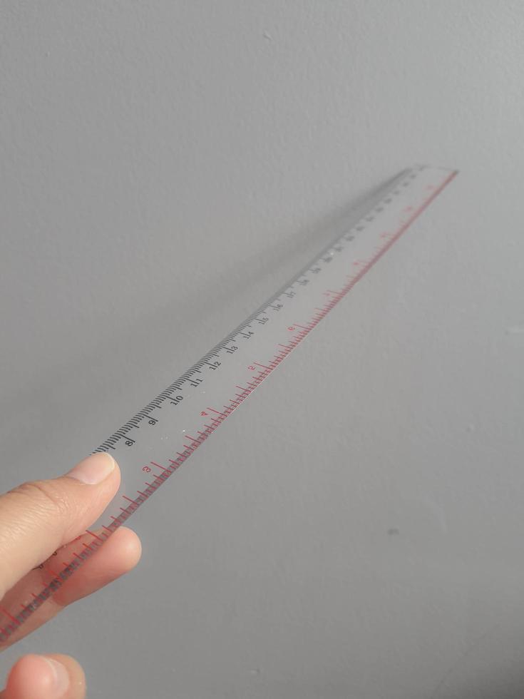 A hand is holding a plastic ruler. photo