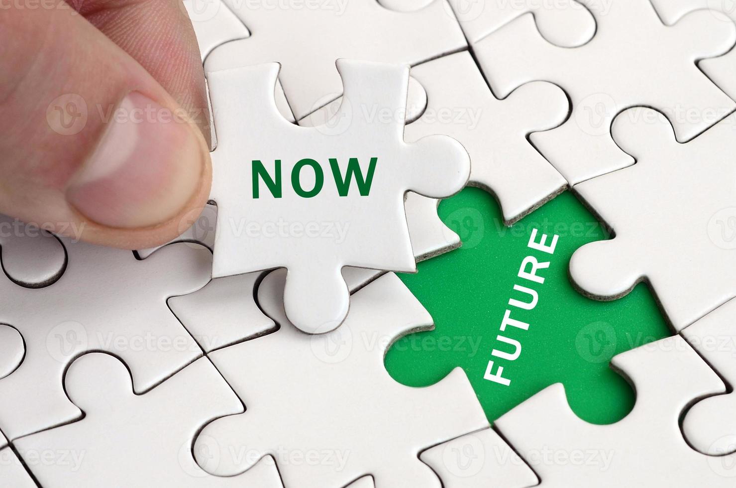 The human hand fills the last missing elements of the surface from the jigsaw puzzle. Image with words now and future photo