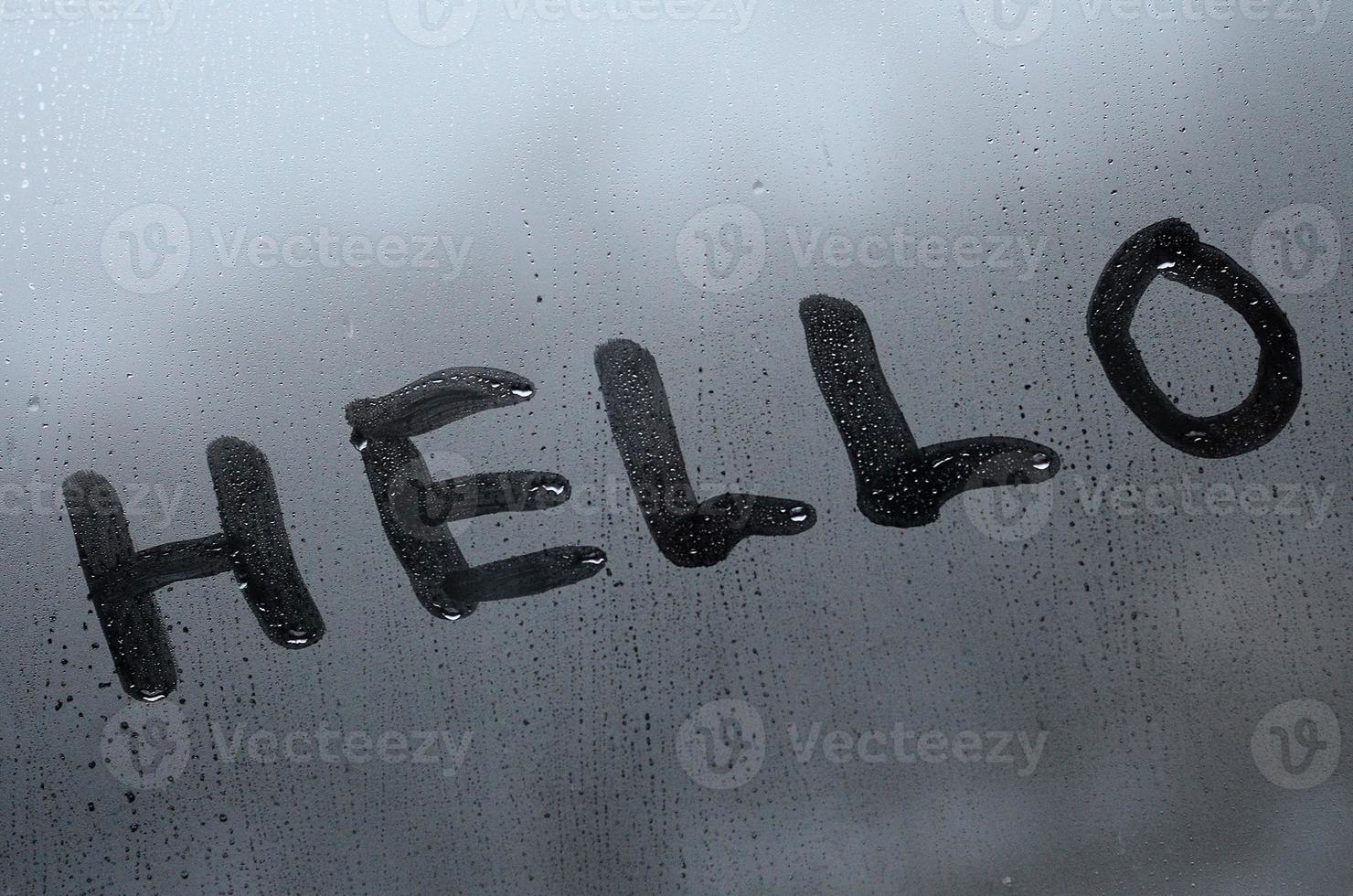 The English word Hello is written with a finger on the surface of the misted glass photo