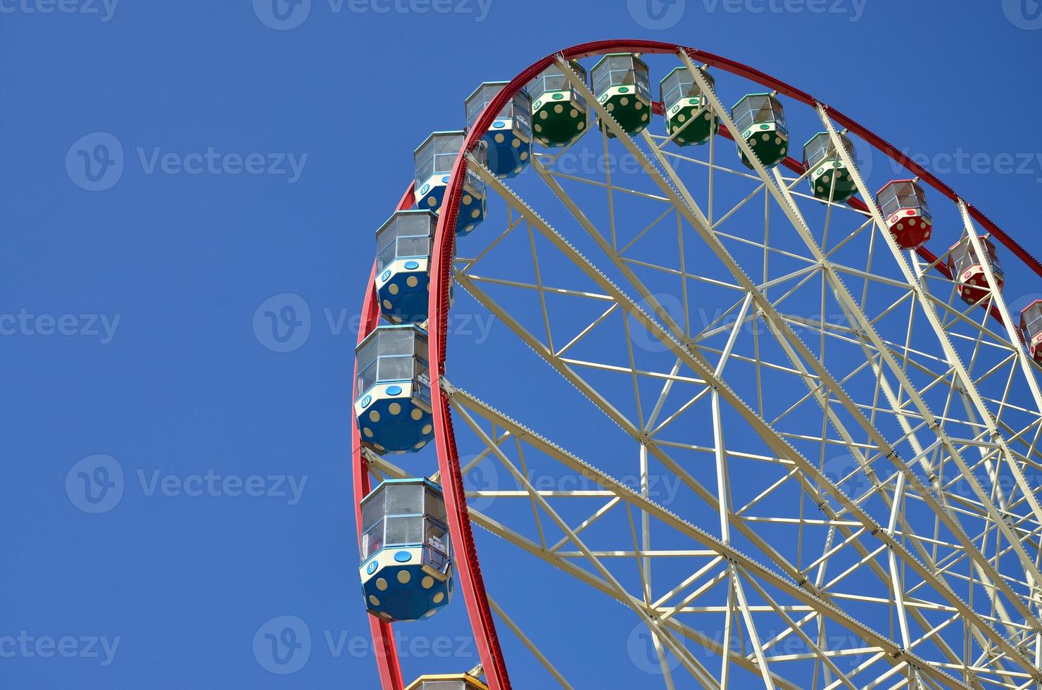 Big and modern multicolour ferris wheel on clean blue sky background photo