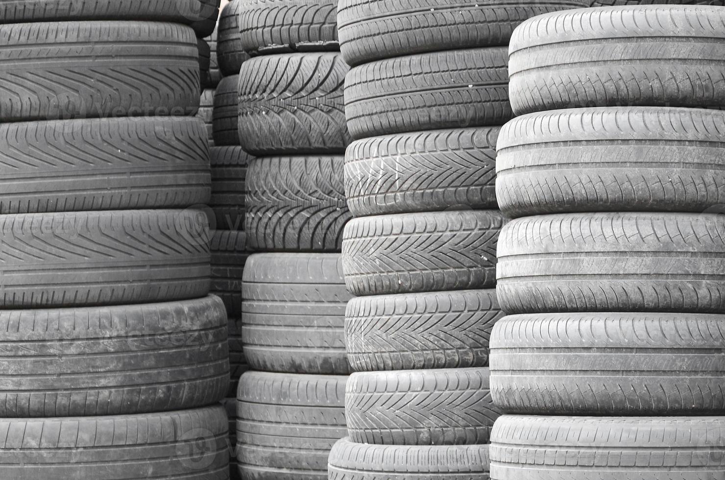 Old used tires stacked with high piles in secondary car parts shop garage photo