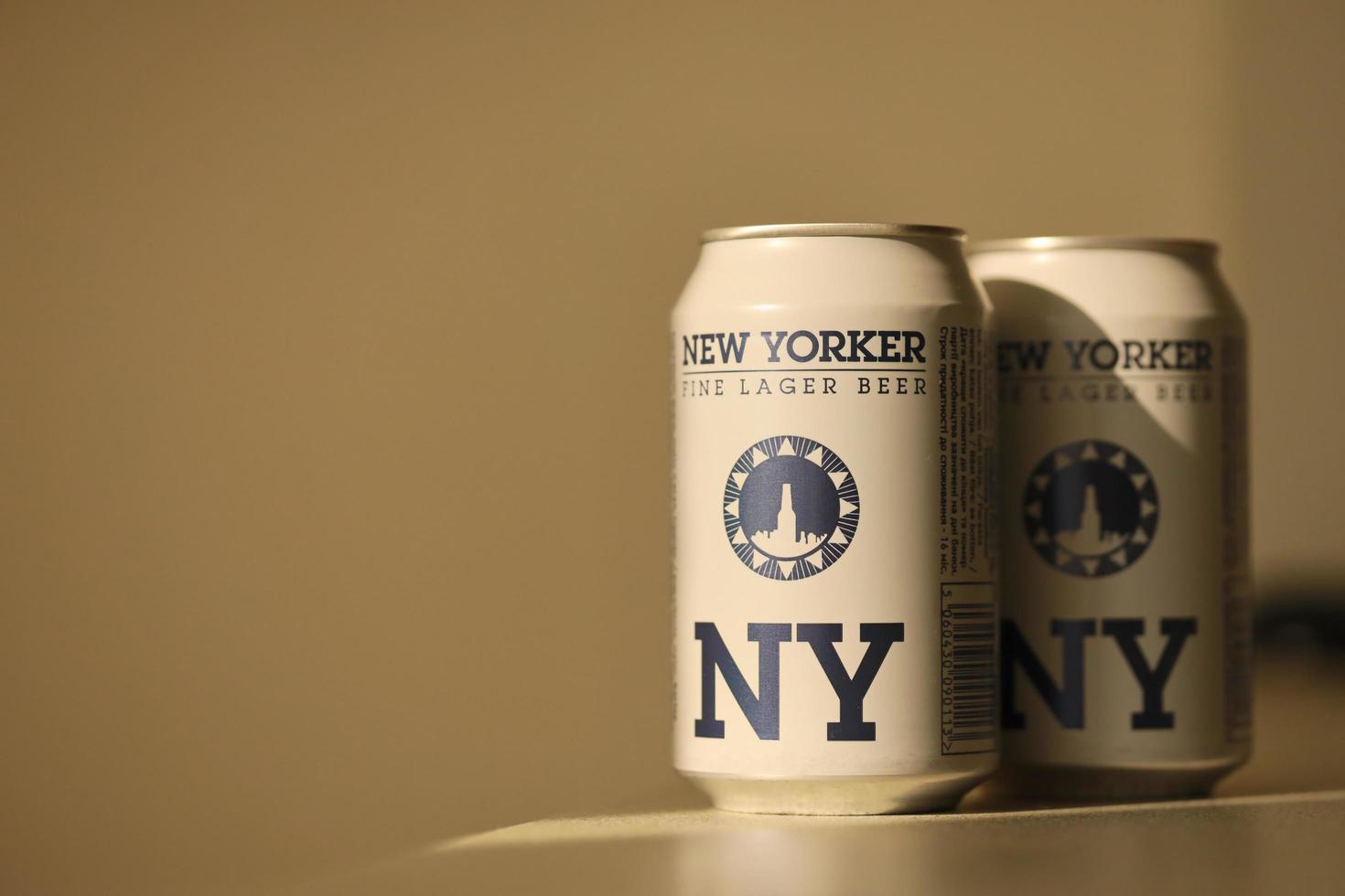 TERNOPIL, UKRAINE - JULY 18, 2022 Two cans of New Yorker fine lager beer with original logo and design on brown retro background photo