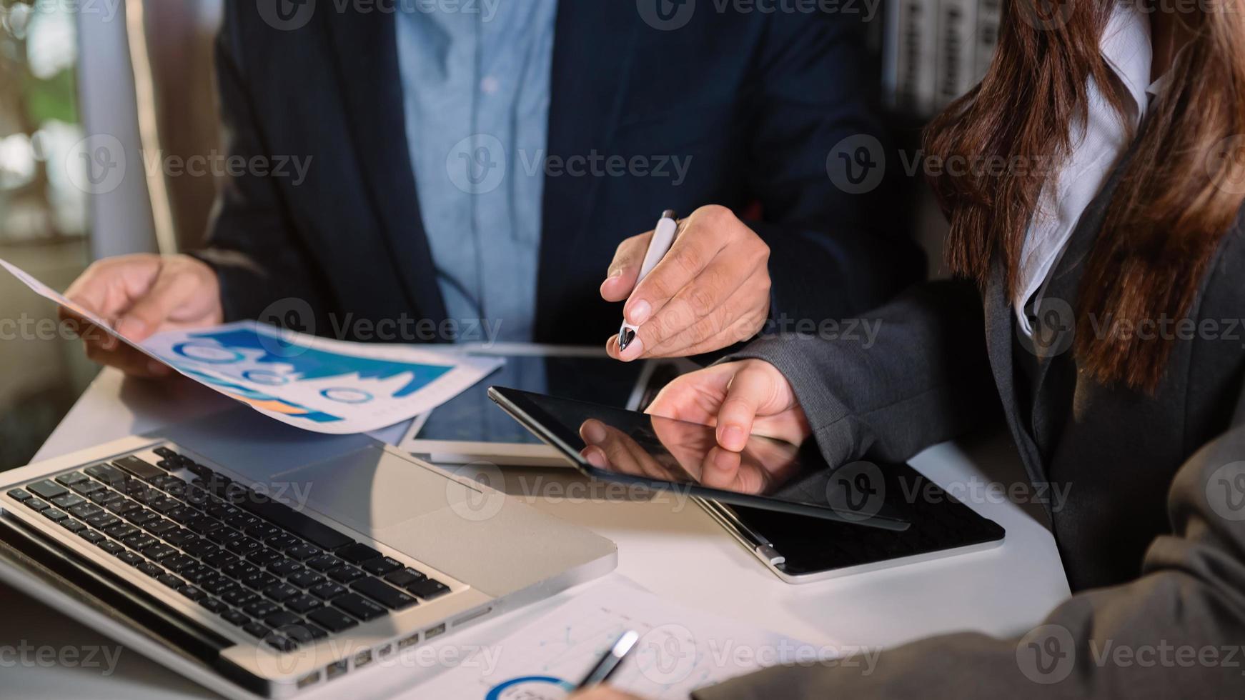 socios comerciales discutiendo documentos e ideas con teléfonos inteligentes y tabletas digitales y negocios gráficos en la reunión de trabajo de un nuevo proyecto de puesta en marcha. tarea de finanzas. foto