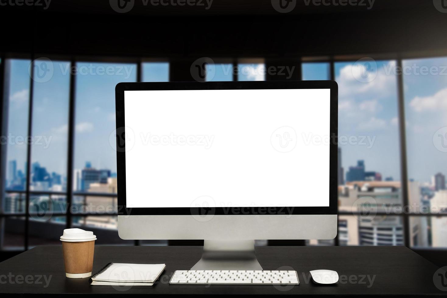 Computer monitor with white blank screen putting on white working desk with wireless mouse and keyboard over blurred vintage office as background. photo