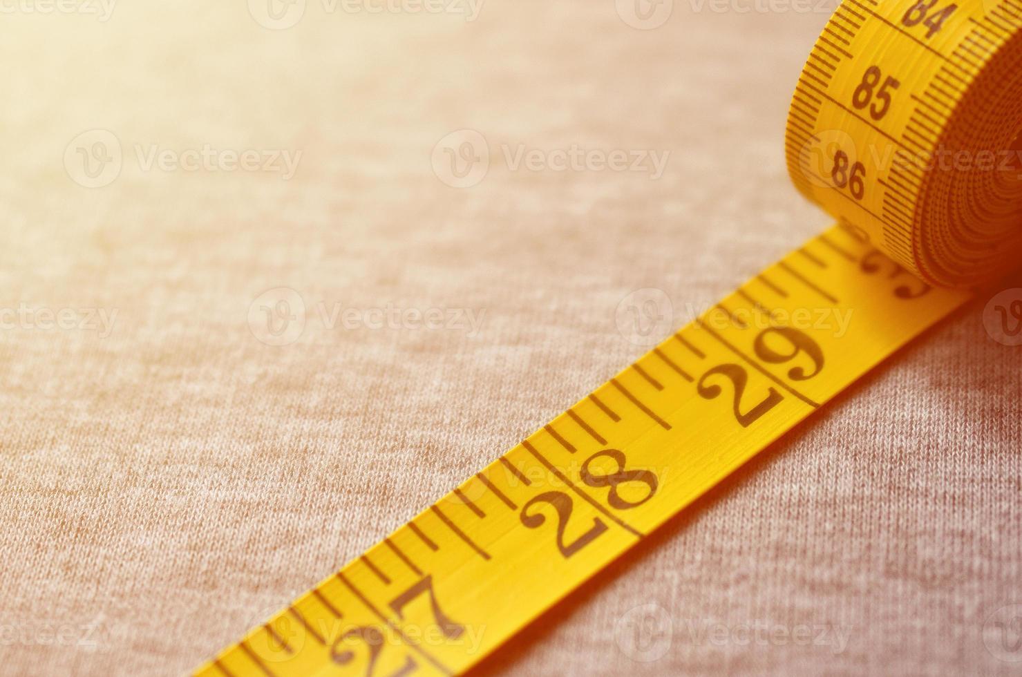 Yellow measuring tape lies on a gray knitted fabric photo