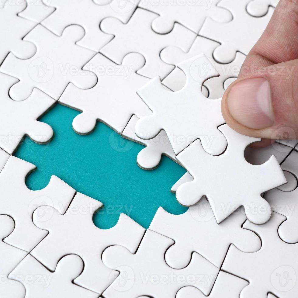 The human hand fills the last missing elements of the surface from the jigsaw puzzle. The concept of the completion of the initiated cases photo