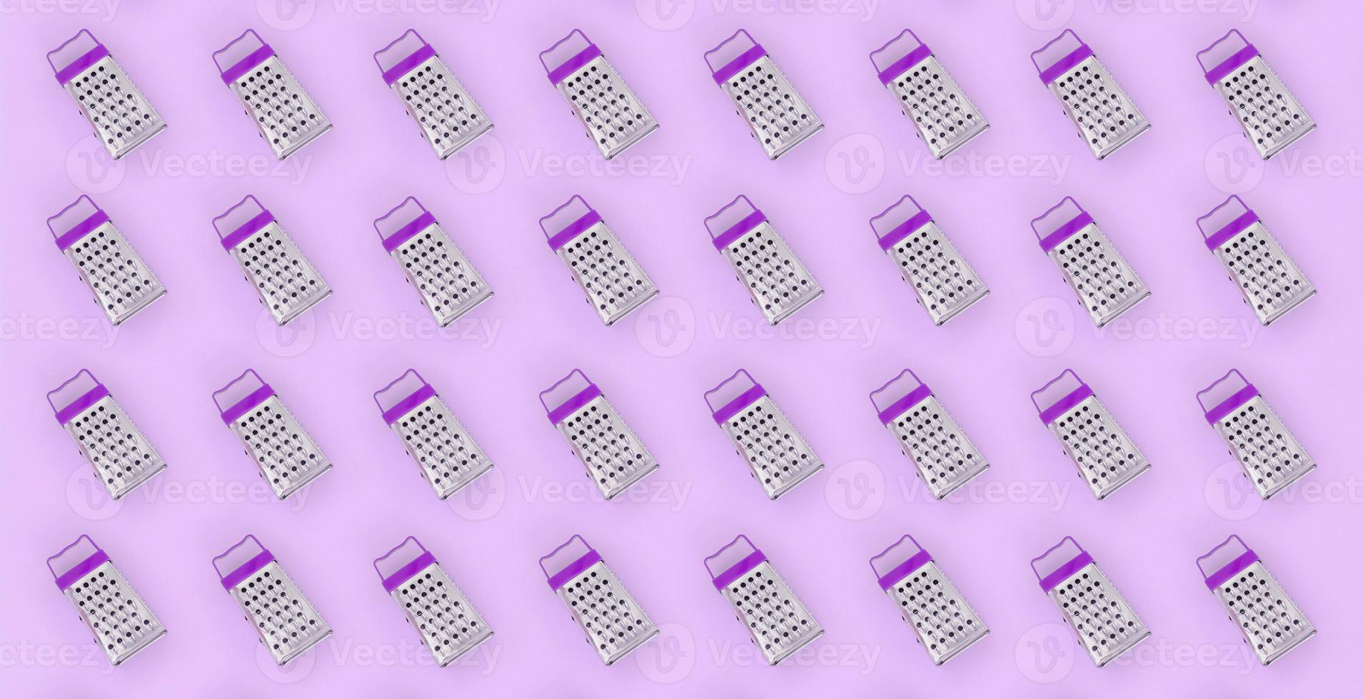 Small stainless steel graters lies on a pastel colored paper. Kitchen accessories. Tools for cooking. Flat lay top view photo
