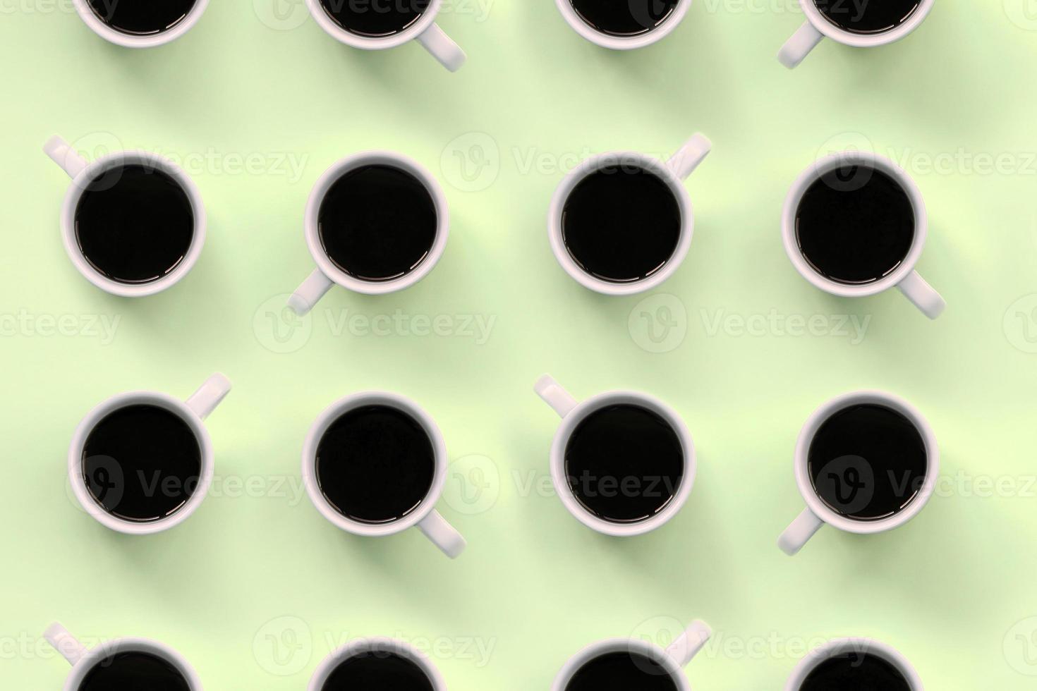 Many small white coffee cups on texture background of fashion pastel lime color paper photo