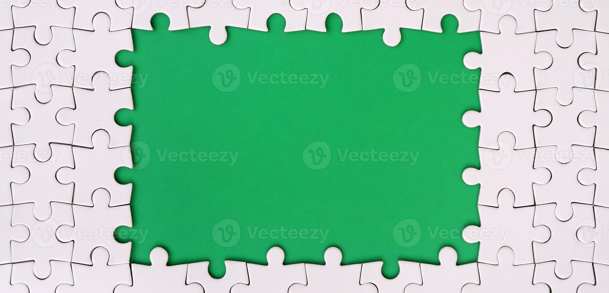 Framing in the form of a rectangle, made of a white jigsaw puzzle around the green space photo