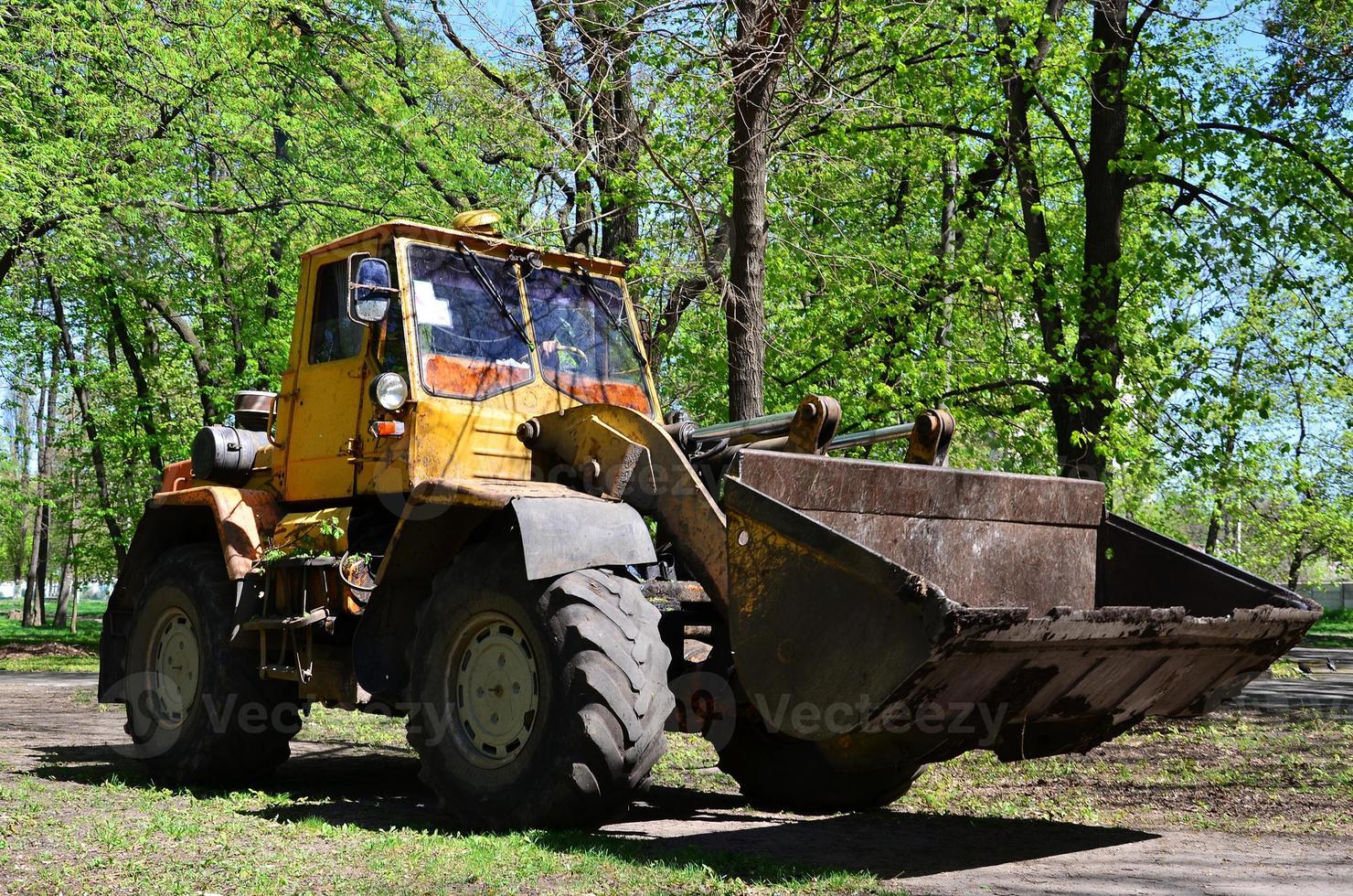 The city improvement team removes the fallen leaves in the park with an excavator and a truck. Regular seasonal work on improving the public places for recreation photo