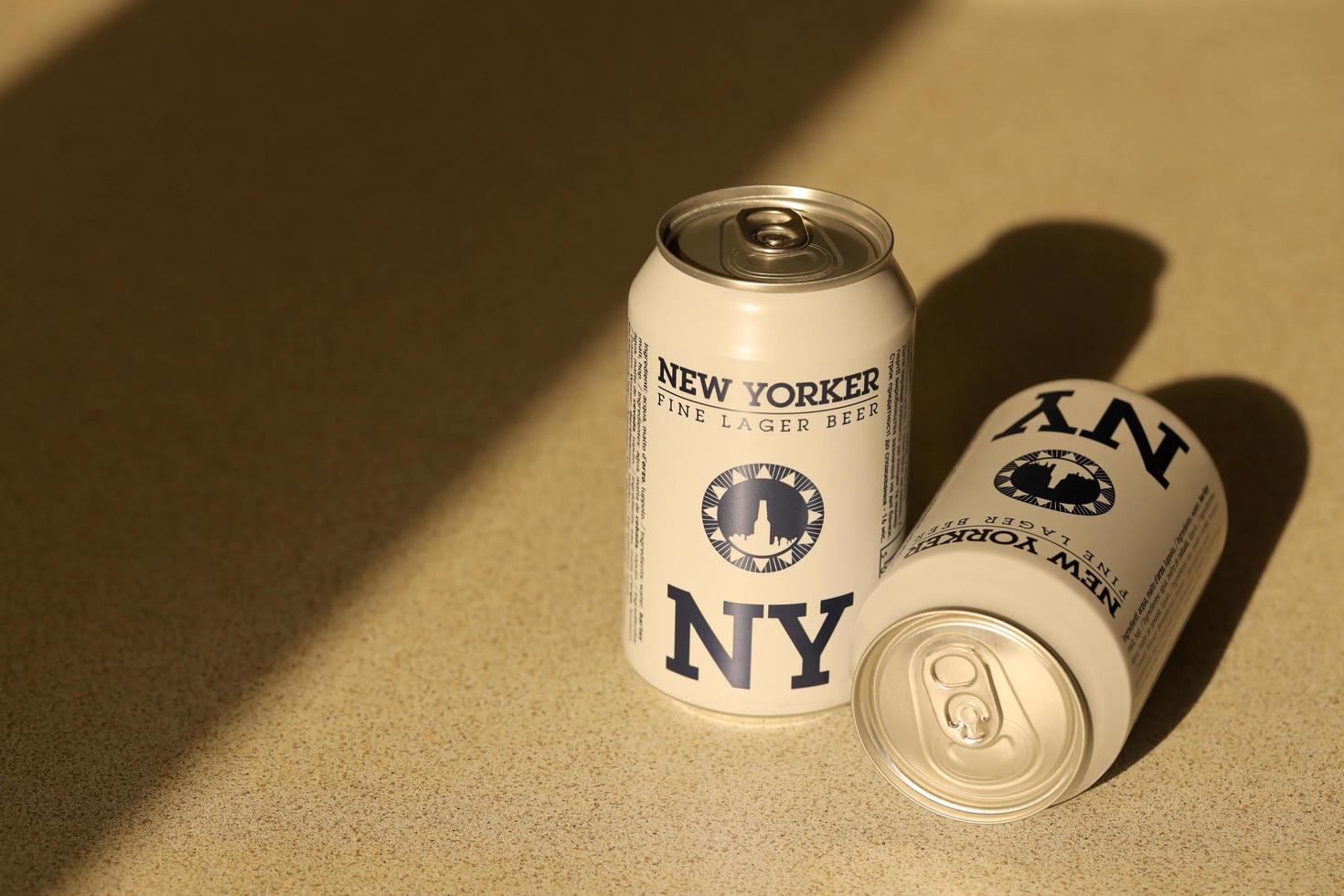 TERNOPIL, UKRAINE - JULY 18, 2022 Two cans of New Yorker fine lager beer with original logo and design on brown retro background photo