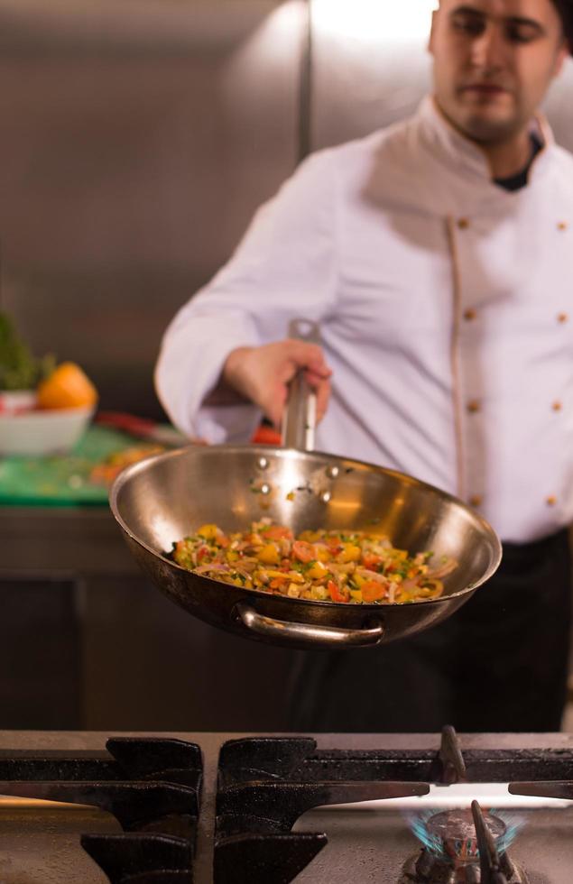 chef volteando verduras en wok foto