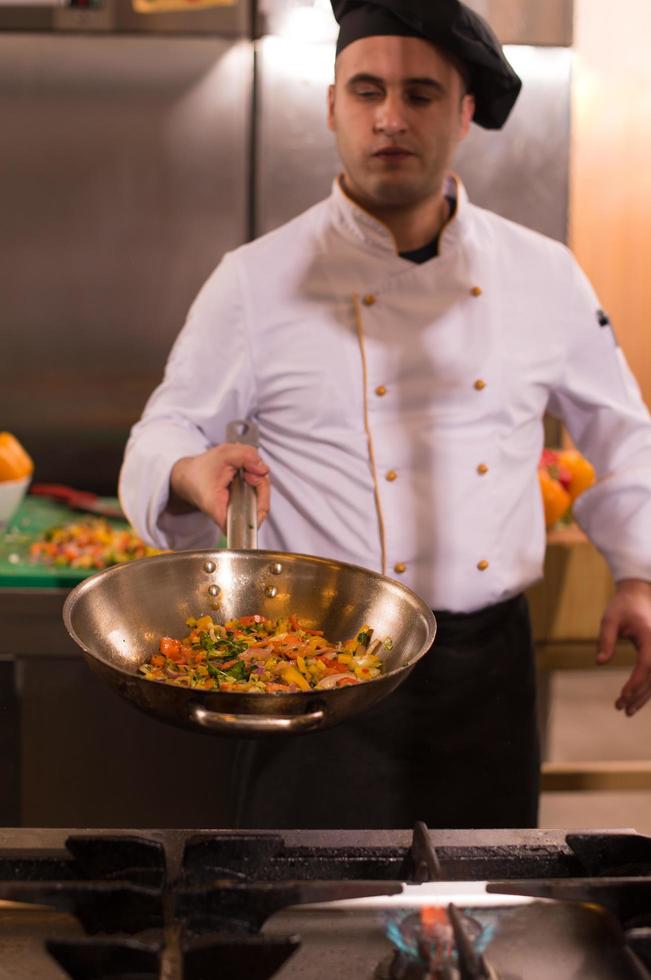 chef volteando verduras en wok foto